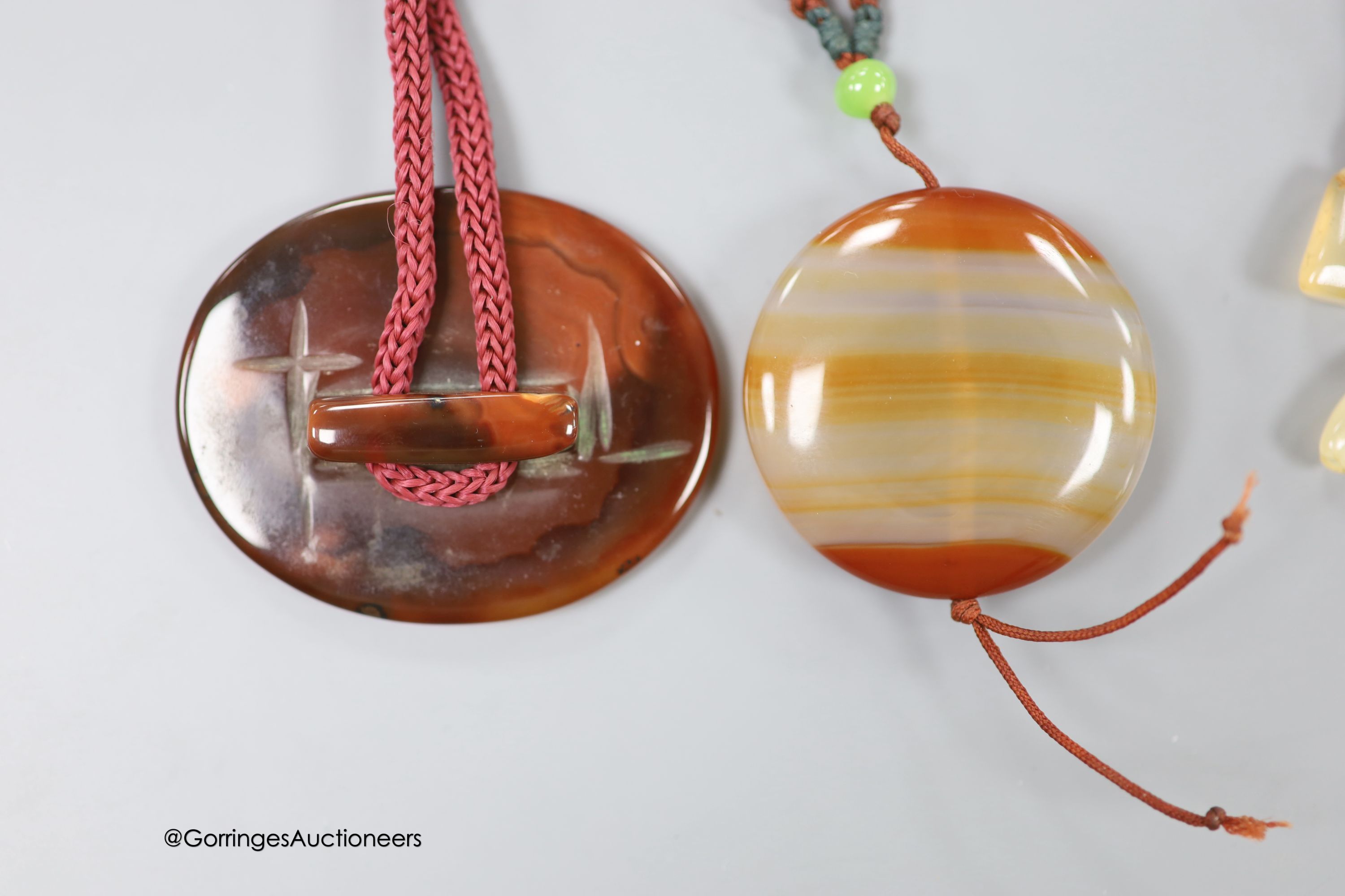 Two agate pendants, on fabric cords, largest pendant 57mm.
